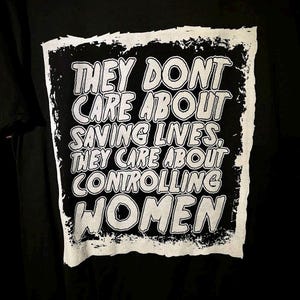 以下が含まれることがあります： 白い文字で「彼らは命を救うことを気にしない、彼らは女性を支配することを気にしている」と書かれた黒いTシャツ