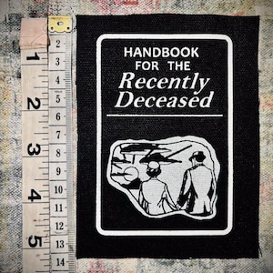 Peut inclure: Patch noir et blanc avec le texte "HANDBOOK FOR THE RECENTLY DECEASED" et une illustration en noir et blanc de deux personnes qui s'éloignent du spectateur.
