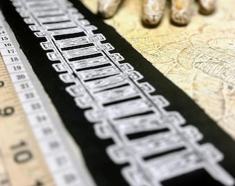 May include: A rectangular black fabric patch featuring a white screen-printed graphic of railroad tracks. The patch is positioned alongside a yellow measuring tape showing measurements in inches, with the patch length exceeding 10 inches.