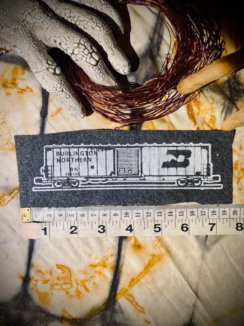May include: A black and white illustration of a Burlington Northern train car with the number 3 on the side. The car is on a gray background and is about 8 inches long.