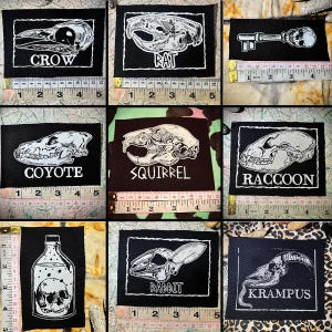 Op de afbeelding: Negen zwarte patches met witte illustraties en tekst. De patches tonen afbeeldingen van dierenschedels, een sleutel met een schedel en een fles met een schedel. De tekst bevat "CROW", "RAT", "COYOTE", "SQUIRREL", "RACCOON", "RABBIT" en "KRAMPUS".