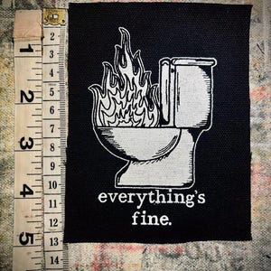 May include: Black and white embroidered patch featuring a toilet on fire with the text "everything's fine."