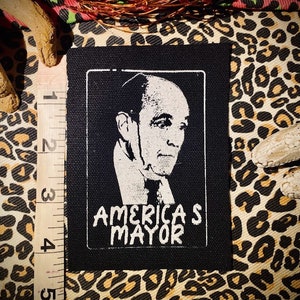 Può includere: Toppa termoadesiva in bianco e nero con un ritratto di un uomo e il testo "America's Mayor".