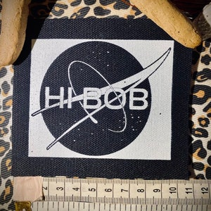 May include: Black and white patch with a NASA-inspired logo featuring a circle with a curved line and the text "HIBOB" in white.