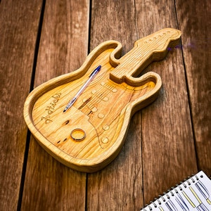 May include: A wooden guitar-shaped serving tray with the word "J.Stickles" engraved on the side. The tray has a ring and a pen inside.