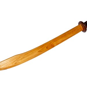 Puede incluir: Una espada de madera con una hoja larga y curva de color marrón claro con un patrón de veta de madera visible. El mango es de color marrón oscuro con bandas horizontales negras envueltas alrededor, terminando en un pomo y una guarda.