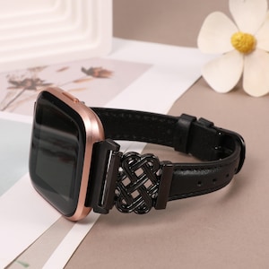 Puede incluir: Una correa de reloj de cuero negro con una esfera de reloj de oro rosa y un cierre met&aacute;lico decorativo. El cierre presenta un dise&ntilde;o tejido.