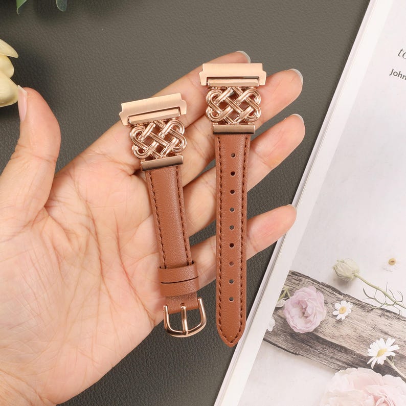 Puede incluir: Dos correas de reloj de cuero marr&oacute;n con cierres de metal dorado rosa y un dise&ntilde;o tejido. Las correas se muestran en una mano.