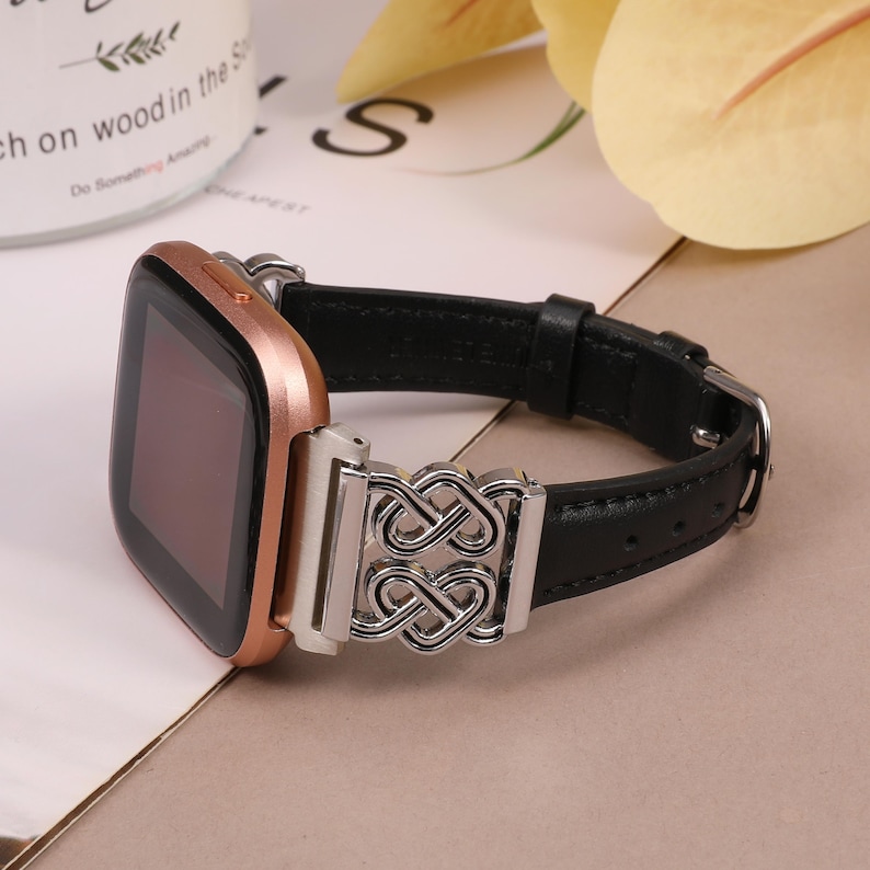 May include: A rose gold smartwatch with a black leather band and a silver infinity symbol buckle.