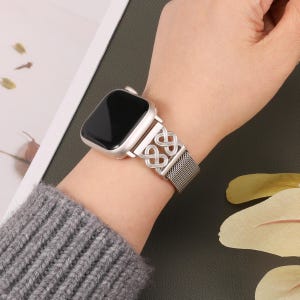 May include: A silver metal watch band with a linked chain design. The band is compatible with Apple Watch.