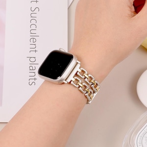 May include: A silver and gold chain link Apple Watch band. The band is made of two rows of chain links, with the top row being gold and the bottom row being silver.