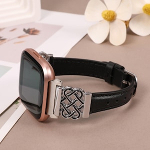 Puede incluir: Una correa de reloj de cuero negro con un cierre de metal plateado y negro con un dise&ntilde;o de nudo intrincado. La correa es compatible con los relojes inteligentes.