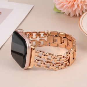 May include: A rose gold Apple Watch band with a chain link design. The band is made of metal and has a polished finish.