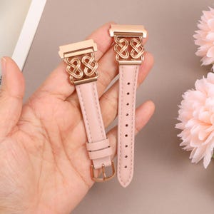 May include: Two pink leather watch bands with gold metal clasps and decorative links. The bands have a woven pattern.