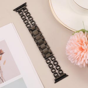 May include: A black metal watch band with a double row of links. The band is designed for an Apple Watch.