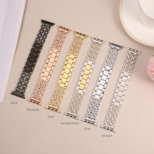 May include: Six different colored metal watch bands for Apple Watch. The bands are in black, rose gold, gold, starlight/gold, silver, and starlight.