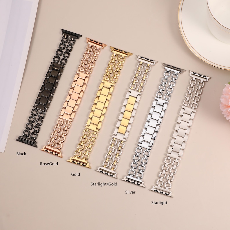 May include: Six different colored metal watch bands for Apple Watch. The bands are in black, rose gold, gold, starlight/gold, silver, and starlight.