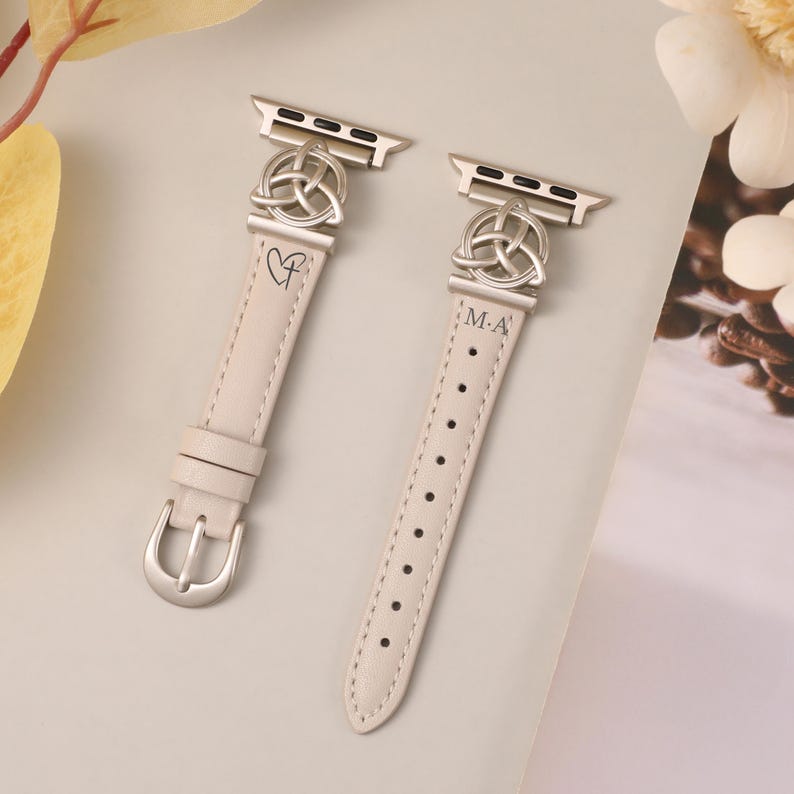 Close-up of Celtic knot Apple Watch band in cream leather, featuring a feminine and symbolic triquetra charm.