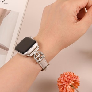 Boho-style brown leather Apple Watch strap with intricate metal Celtic knot charm, ideal for spiritual women.