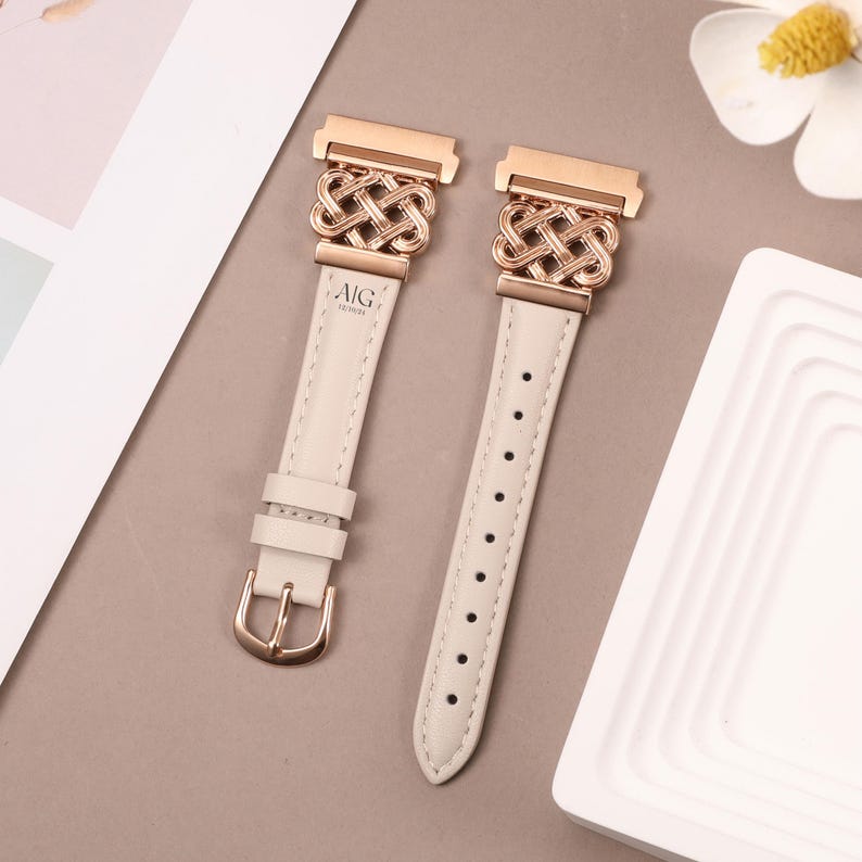 Puede incluir: Dos correas de reloj de cuero blanco con hebillas de oro rosa y un dise&ntilde;o de nudo decorativo. Las hebillas est&aacute;n grabadas con el texto "AIG TOUSHI".