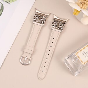 Pode incluir: Duas pulseiras de rel&oacute;gio de couro bege com fechos de metal prateado e designs decorativos de n&oacute;s.