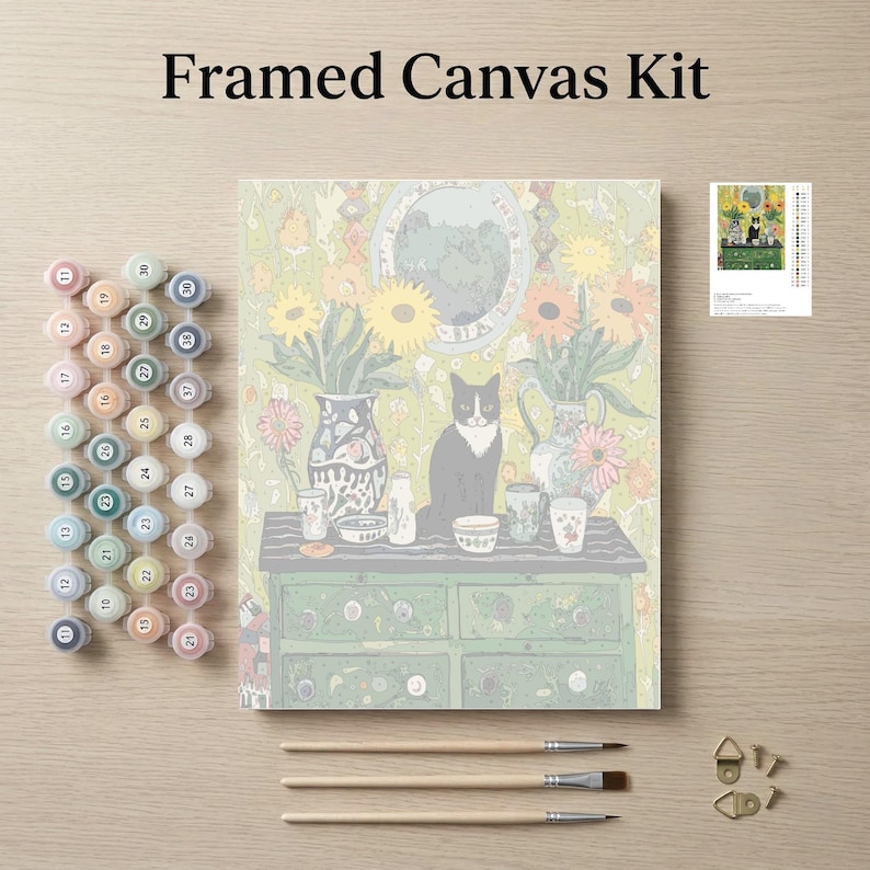 The image is a framed canvas kit featuring a painting of a cat sitting on a table surrounded by various objects, such as vases, cups, and a clock. The kit also includes paintbrushes, paint tubes, and a small picture frame.
