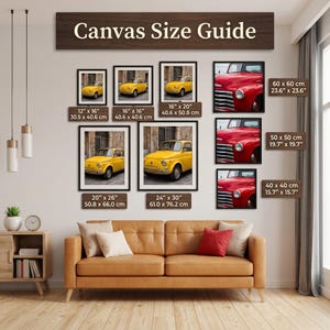 The image is a living room with a brown leather couch and a wooden side table. Above the couch, there is a wooden sign displaying a canvas size guide for artwork, including images of various cars and a clock.