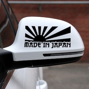 May include: A white car side mirror with a black sticker that says "Made in Japan" and a stylised black rising sun graphic.