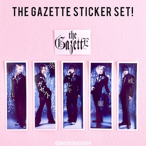 May include: A set of five stickers featuring the Japanese rock band The Gazette. Each sticker features a different band member in a black suit against a blue background. The band members' names are written in Japanese on the stickers. The stickers are printed with the band's name "The Gazette" in a gothic font.
