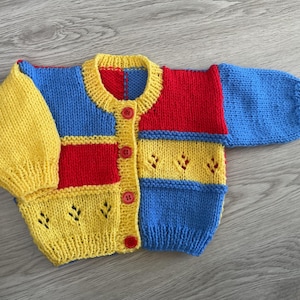 Hand knitted baby cardigan in Red, Blue & Yellow.