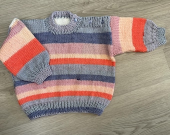 May include: A hand-knitted baby sweater with horizontal stripes in shades of blue, pink, orange, and gray. The sweater has a round neckline with three small buttons and long sleeves. The garment is made of soft yarn.