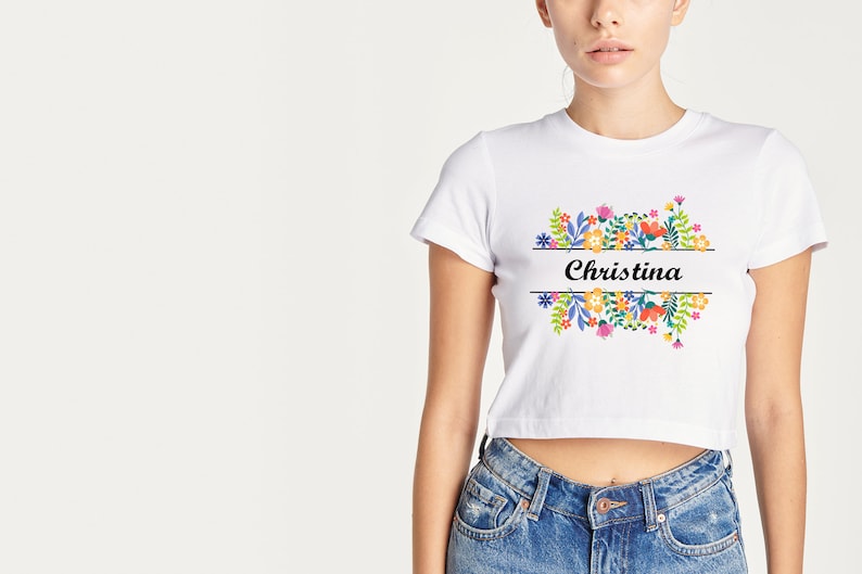 May include: White cropped t-shirt with a floral design and the name "Christina" printed on the front.