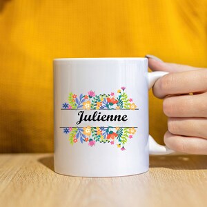 May include: White ceramic mug with a floral design and the name "Julienne" printed on it.