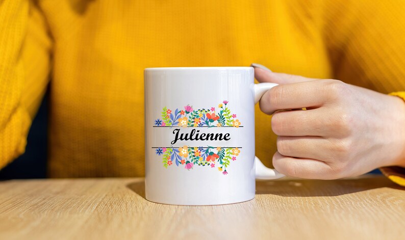 May include: White ceramic mug with a floral design and the name "Julienne" printed on it.