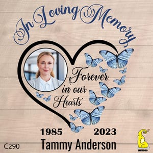 May include: A heart-shaped memorial with a photo of a woman, surrounded by blue butterflies. The text "In Loving Memory" is at the top, and "Forever in our Hearts" is inside the heart. The dates 1985 and 2023 are at the bottom, along with the name "Tammy Anderson".