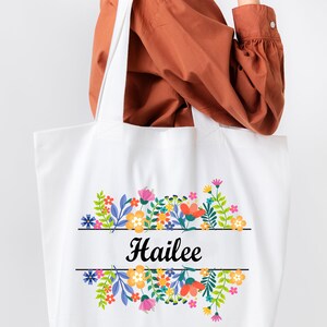May include: White tote bag with a floral design and the name "Hailee" printed in black.