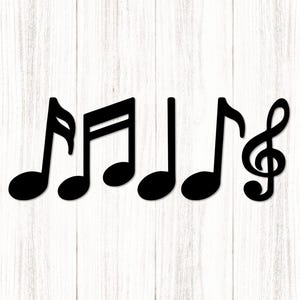 Puede incluir: Notas musicales negras y una clave de sol dispuestas sobre un fondo de madera blanca. Las notas incluyen una corchea, una blanca y una redonda. La clave de sol está a la derecha.