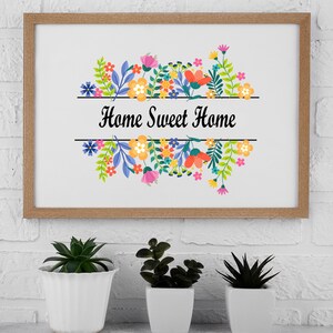 May include: A framed print with a floral design and the text "Home Sweet Home". The print is in a wooden frame and is hanging on a white brick wall.
