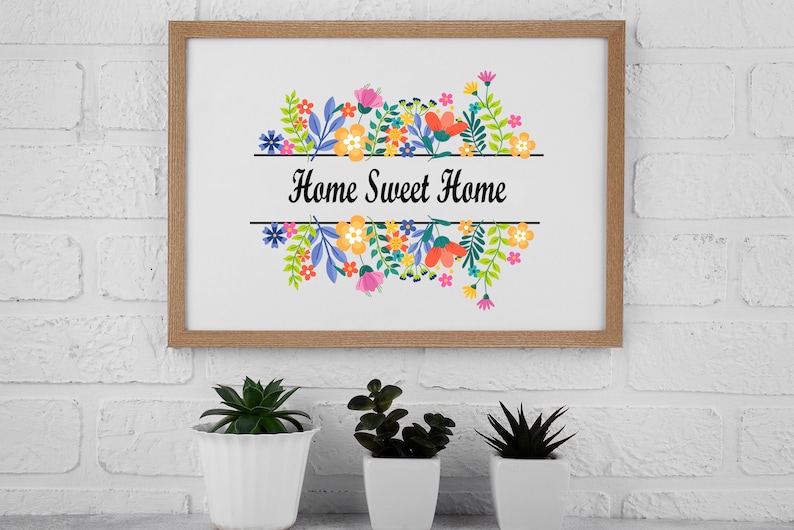 May include: A framed print with a floral design and the text "Home Sweet Home". The print is in a wooden frame and is hanging on a white brick wall.