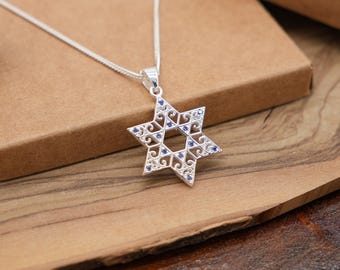 May include: A silver Star of David pendant necklace with blue crystal accents. The pendant is intricately designed with a filigree pattern.