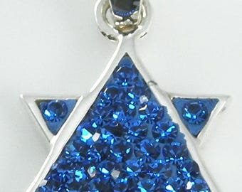 May include: A silver-toned Star of David pendant featuring a central triangular inlay filled with small, faceted, deep blue crystals. The six-pointed star design is framed in polished metal and includes a matching silver-toned bail at the top.