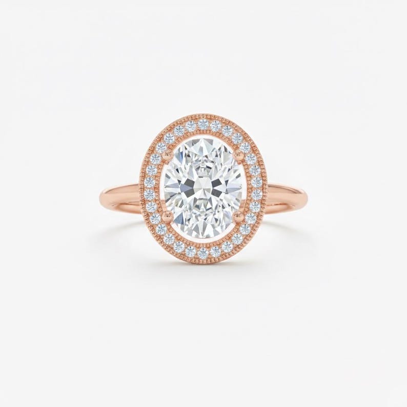 K&ouml;nnte beinhalten: Verlobungsring aus Ros&eacute;gold mit einem oval geschliffenen Diamanten. Der Diamant wird von einem Halo aus kleineren Diamanten umgeben. Der Ring hat ein zartes Ros&eacute;goldband. Klassisches Design.