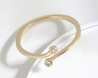 May include: A gold ring with two small clear stones. The ring is open and can be adjusted to fit different finger sizes.