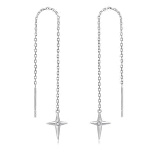 以下が含まれることがあります： シルバーのスレッダーピアス。各ピアスは、曲線を描き星型のデザインで終わる繊細なチェーンが特徴です。各星の中心には、小さな透明な石がセットされています。ピアスは白い背景に表示されています。