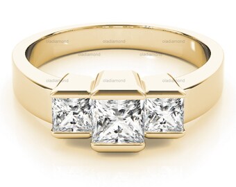 Puede incluir: Un anillo de banda de oro con tres diamantes de forma cuadrada engastados en el centro. Los diamantes están engastados con garras y tienen un corte claro y brillante.