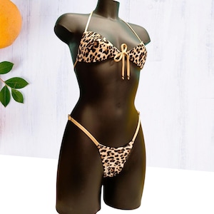 Puede incluir: Un bikini de estampado de leopardo con un lazo de color marrón claro en la parte delantera.