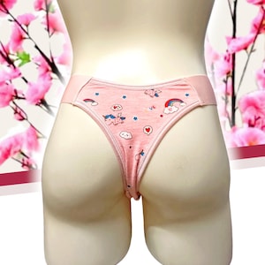 Peut inclure: String rose avec un motif fantaisiste d'licornes, d'arcs-en-ciel, de nuages et d'étoiles. Le sous-vêtement a une ceinture et une bordure rose clair. Le fond présente des fleurs roses.