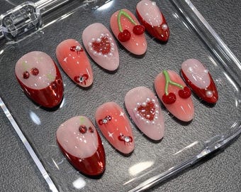 Unhas postiças de tamanho médio amendoado para o Dia dos Namorados, com laço prateado e coração, detalhes em vermelho. Arte de unhas feita à mão para uso diário ou para presentear.