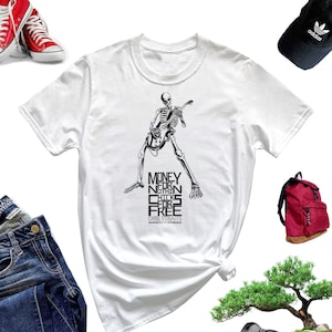 Puede incluir: Camiseta blanca con una ilustración en blanco y negro de un esqueleto tocando una guitarra. El texto "Money for Nothing Chicks for Free" y "Dire Straits" está impreso en la camiseta.