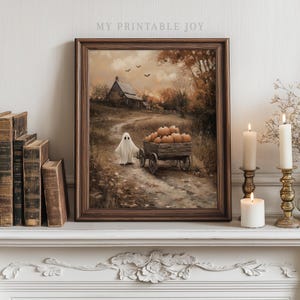 Puede incluir: Una impresión enmarcada con temática de Halloween. La obra de arte representa un fantasma, un carro lleno de calabazas y un paisaje rural. La impresión está en un marco de madera marrón. El texto "MY PRINTABLE JOY" está en la parte superior.
